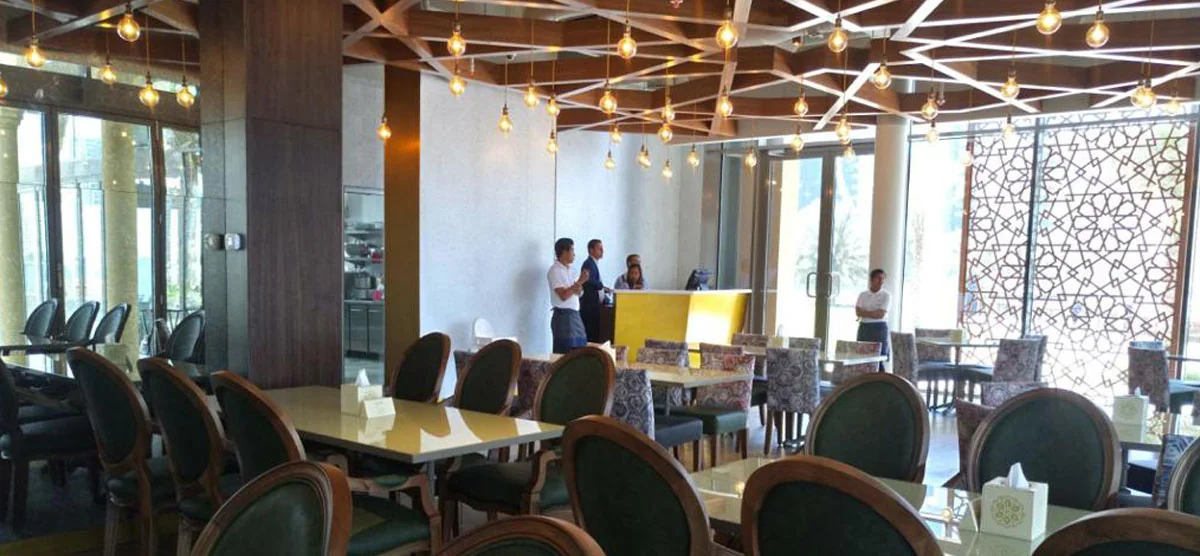 Restaurant dining area with geometric ceiling and green upholstered seating